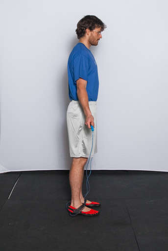 Stand with your feet approximately hip width apart and your arms down at your side, holding the jump rope behind you.
