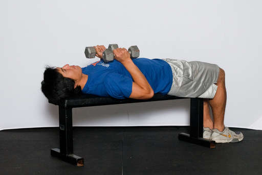 Lie face up on a weight bench with your feet flat on the floor. Hold the dumbbells in an overhand grip.
