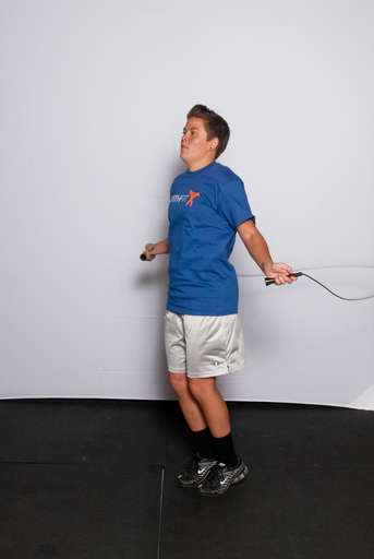 Stand with your feet approximately hip width apart and your arms down at your side, holding the jump rope behind you.
