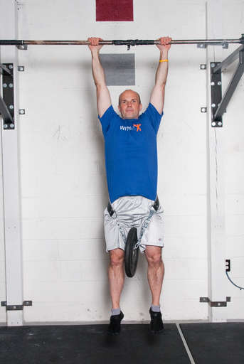 Stand below the pull up bar. Grasp the pull up bar with an overhead grip, with your hands over the bar and approximately shoulder width apart. Attach additional weight via a weight belt, chain, or other method. Hang from the pull up bar, so that your arms and legs are completely straight.
