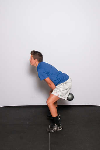 Pushing your butt back and bending your knees slightly, swing the kettlebell back between your legs. Your torso should bend forward and your hips should move back for balance.