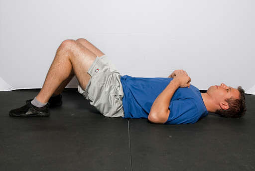 Lie on your back on the floor with your legs bent at a 90 degree angle. Place your hands in front of your chest.