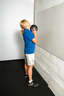 Stand about 1-2 feet away from the wall with your feet shoulder width apart. Hold the medicine ball in front of your face with your arms bent.